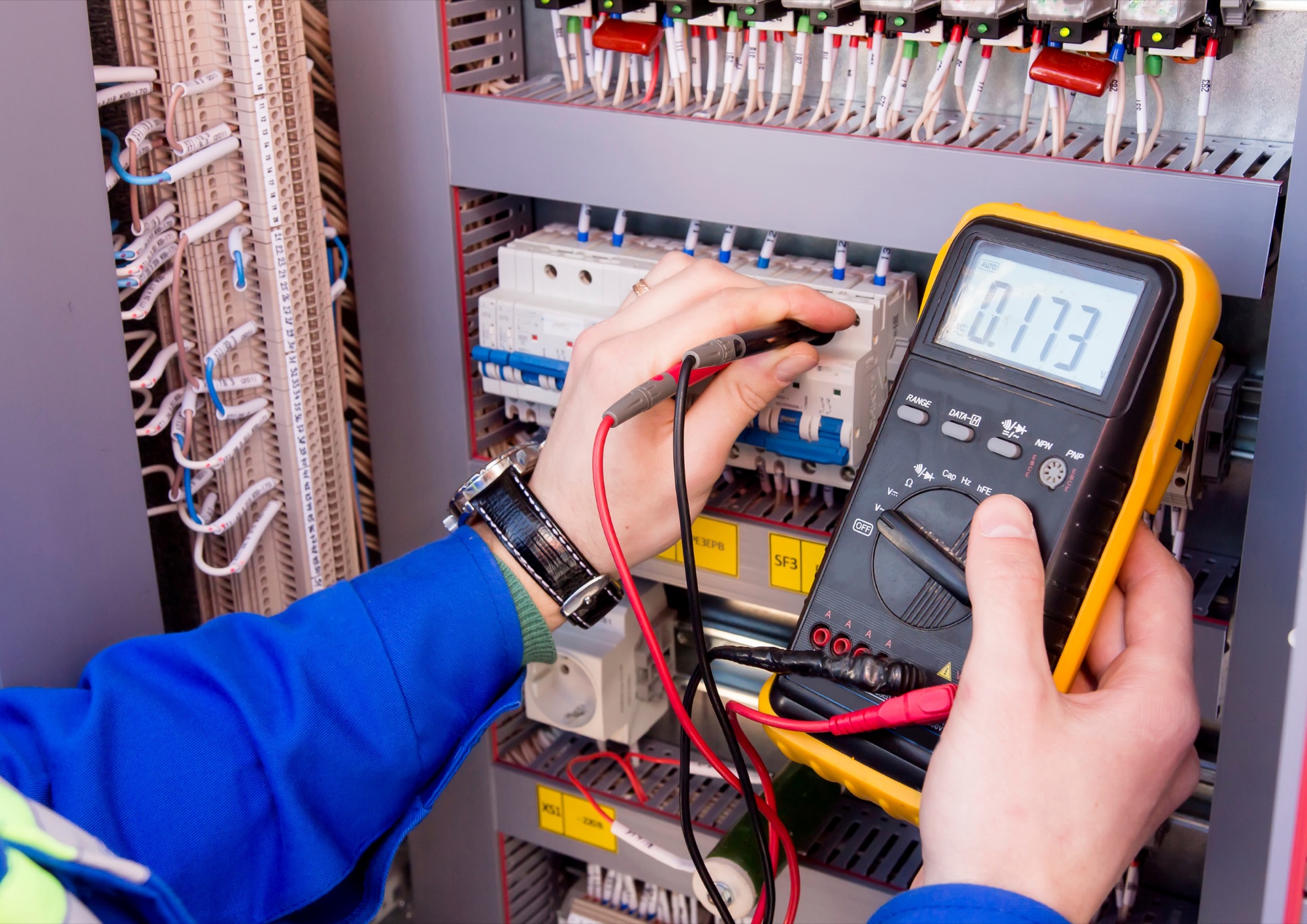Electrician testing an electrical control panel with a multimeter in Dublin, CA